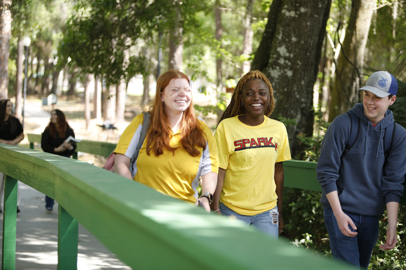 Three students walking across a wooden walkway at the Plant City Campus.